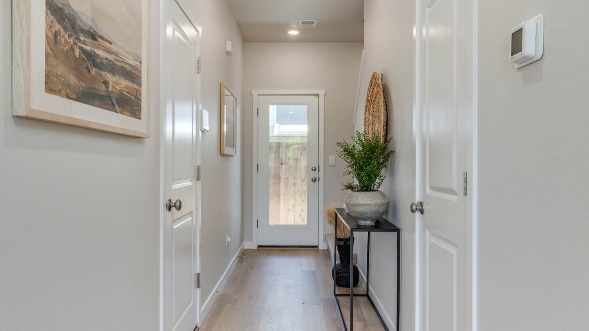 Gordon Creek Pointe Hallway with laminate flooring, white walls, paintings, entryway table, and door