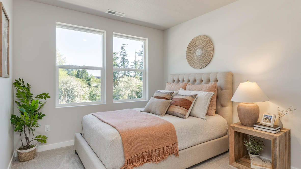 Gordon Creek Pointe bedroom with orange blanket and pillows, plant, windows, and nightstand with lamp