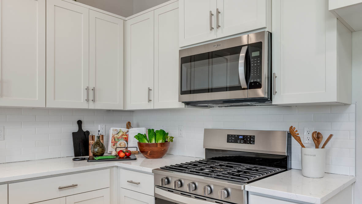 Gordon Creek Pointe Kitchen with quartz countertops, stainless steel appliances, white cabinets, and laminate flooring