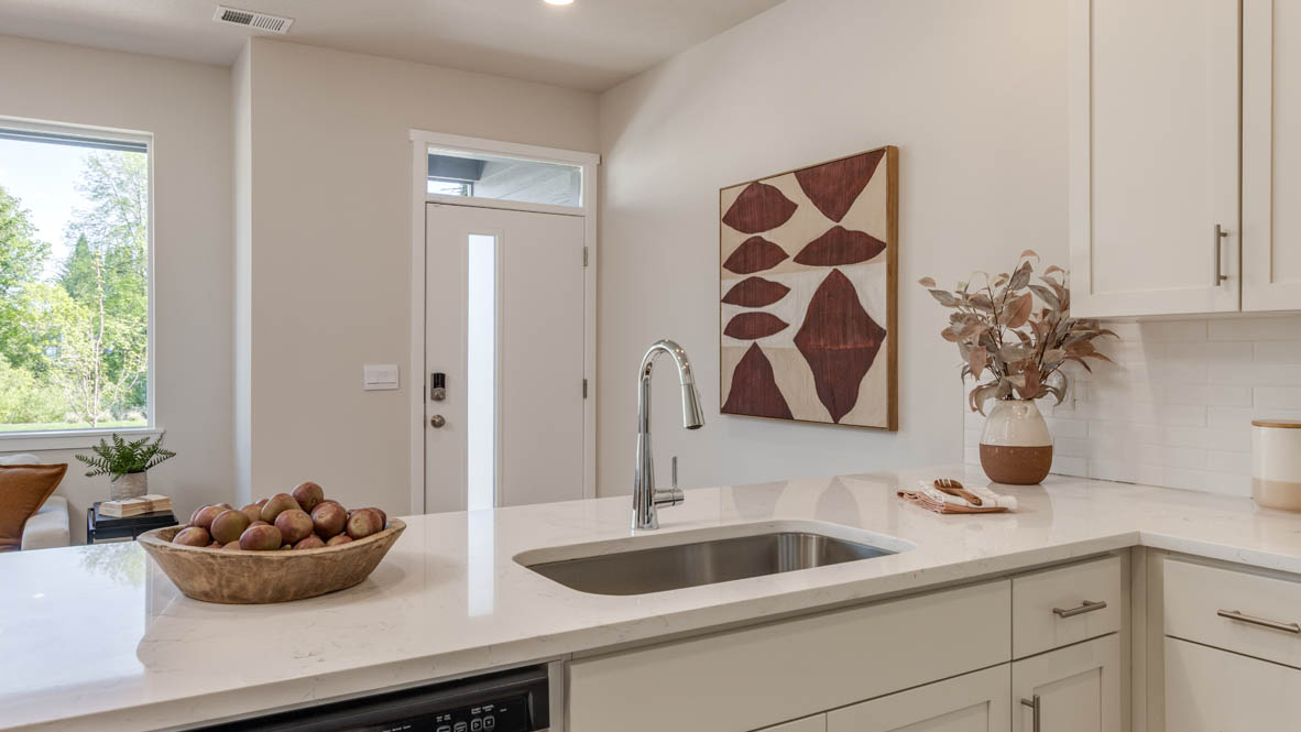 Gordon Creek Pointe Kitchen with stool chairs, quartz countertops, island peninsula, stainless steel appliances, white cabinets, and decorative painting