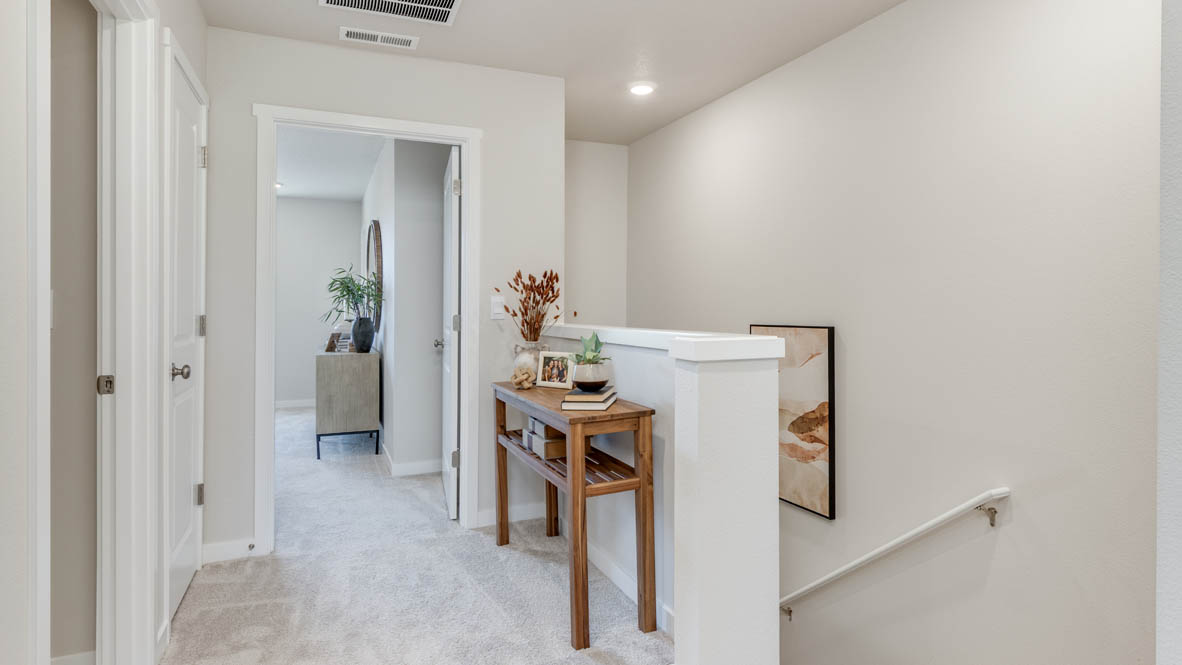 Gordon Creek Pointe hallway with carpet, staircase, and the primary bedroom in the background