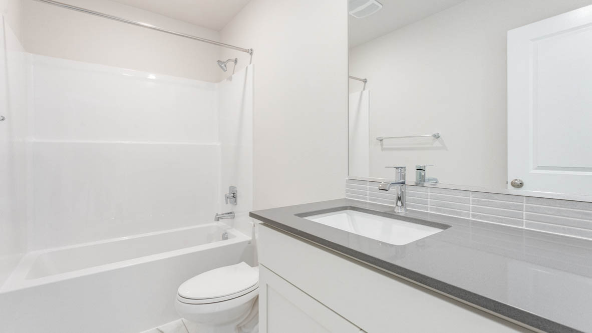 Gordon Creek Pointe secondary bathroom with quartz countertops, toilet, shower tub, mirror