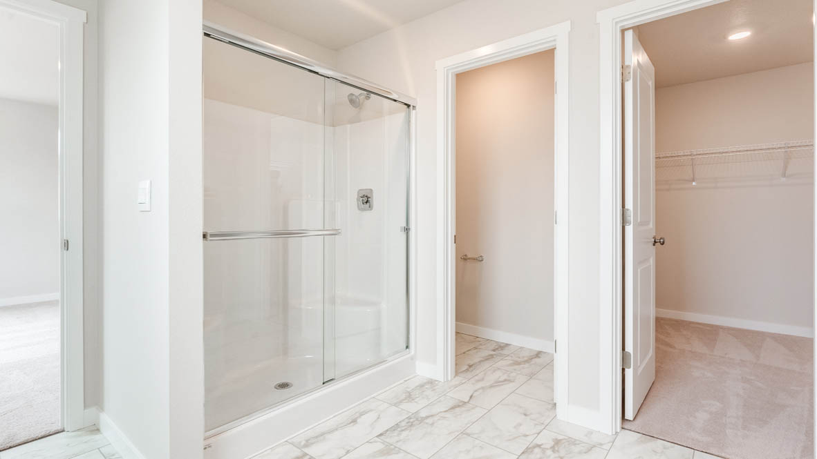 Gordon Creek Pointe primary bathroom with walk in shower, and the walk in closet in the background