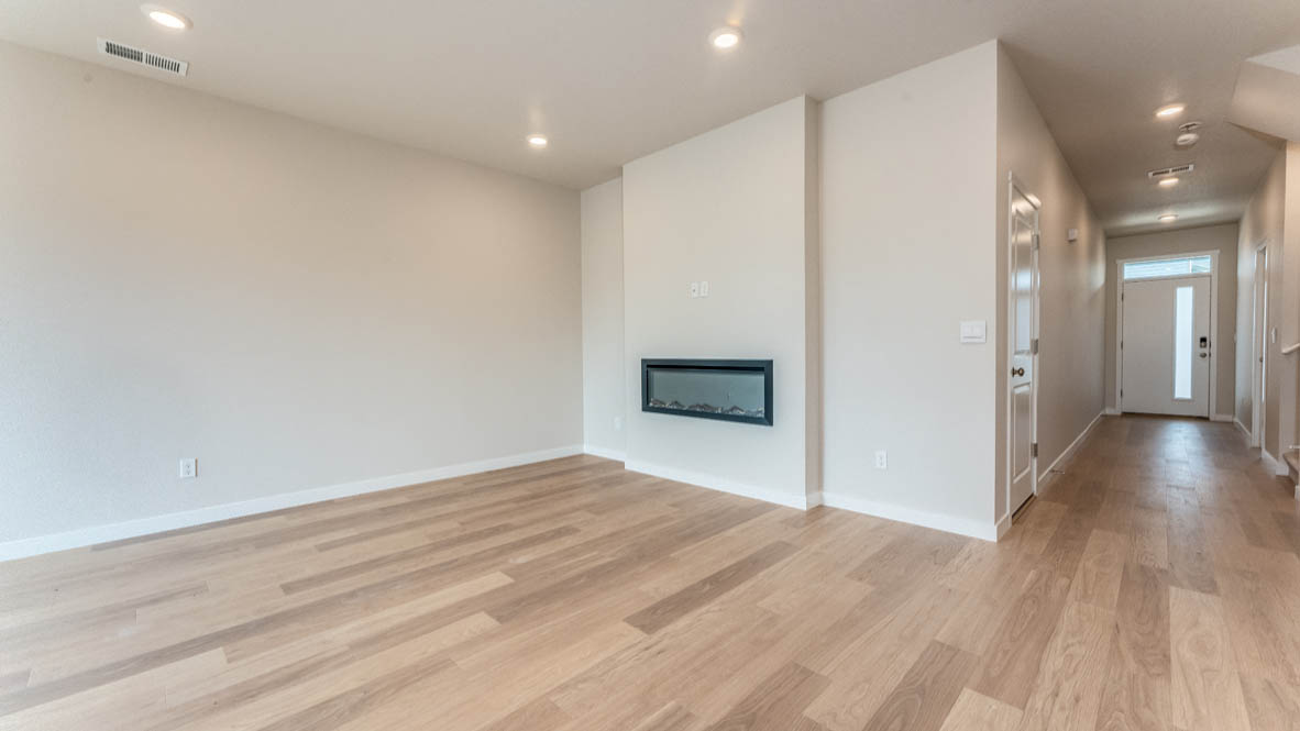 Gordon Creek Pointe great room with a couch, lamp, chair, paintings, coffee table, fireplace and laminate flooring