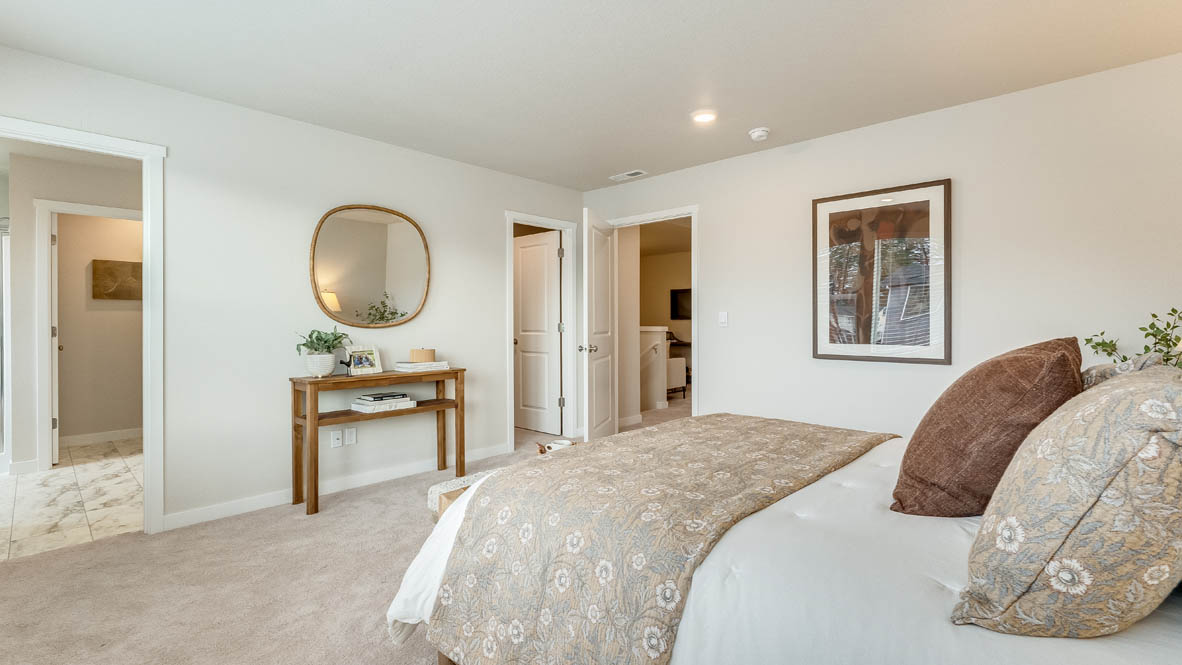 Gordon Creek Pointe primary bedroom with three windows, carpet, bed with two nightstands, comforter