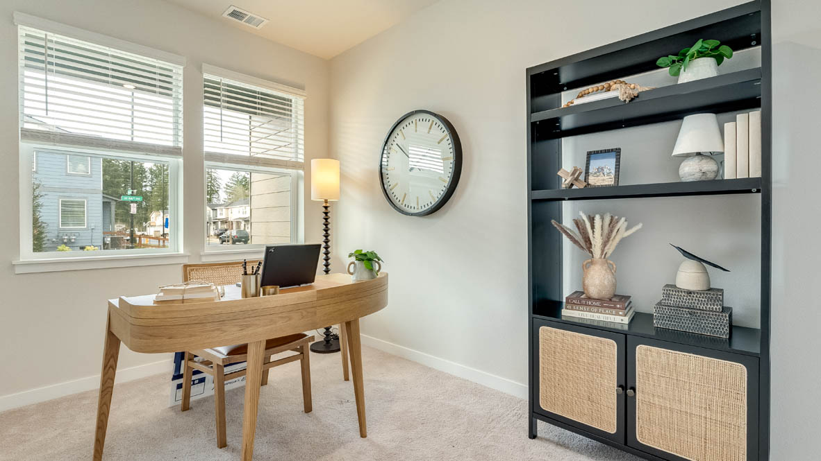 Gordon Creek Pointe bedroom office with a desk, a chair, shelves, plans, a clock, white walls and carpeting and two windows