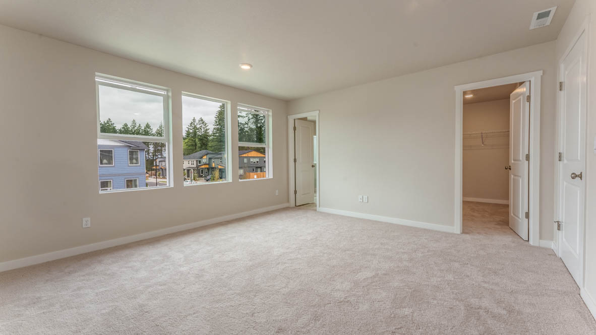 Gordon Creek Pointe primary bedroom with three windows, carpet, bed with two nightstands, comforter