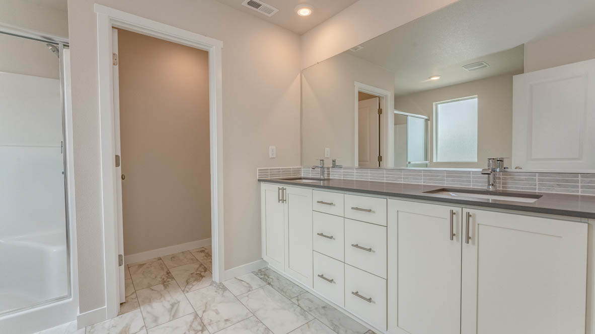 Gordon Creek Pointe primary bathroom with white shaker style cabinets and gray countertops