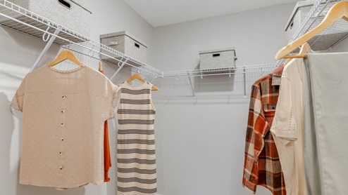 Blue Pearl Walk in closet with white wire shelves and hanging clothes