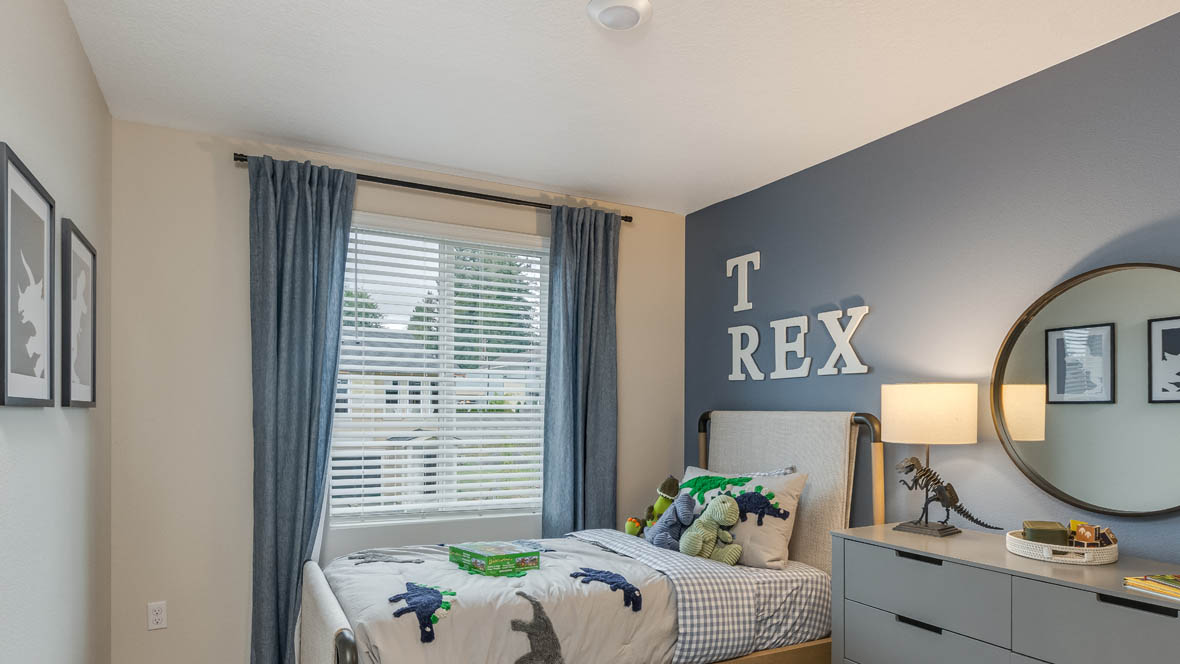 Blue Pearl Bedroom with blue accent wall and dinosaur theme with twin bed, dresser, and a round mirror