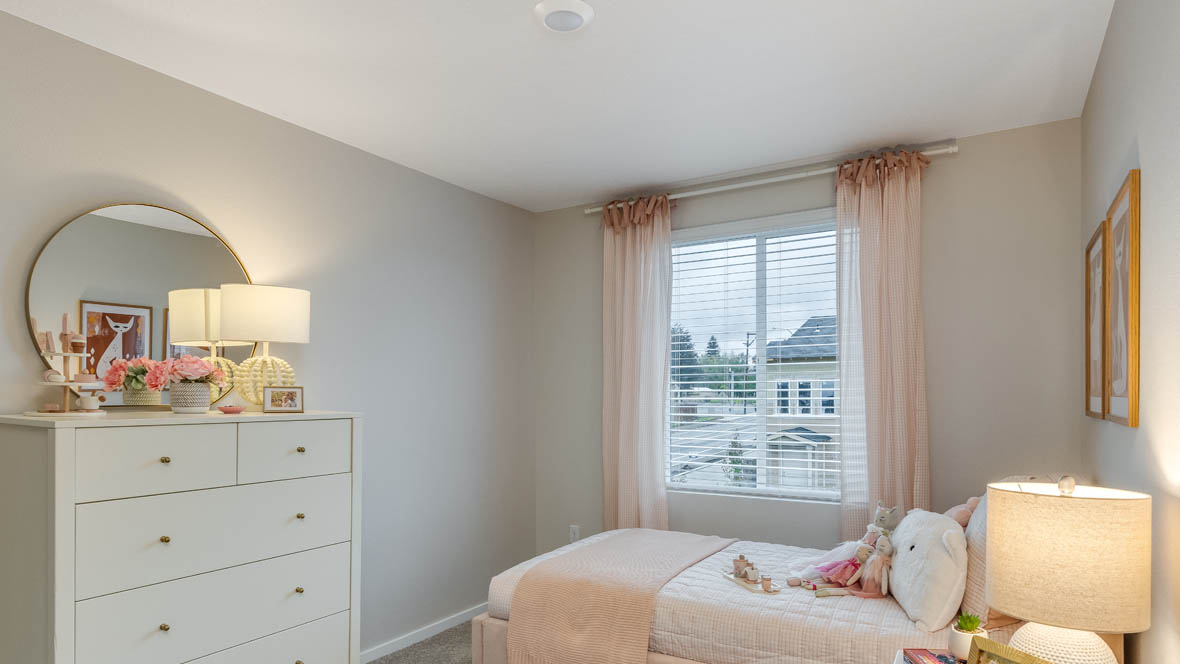 Blue Pearl Bedroom with pink bedding, white walls, a white dresser with pink accents and a bedside lamp