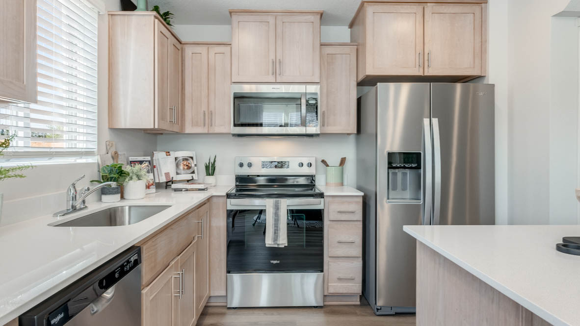 Kitchen with shaker cabinets, quartz counters, stainless steel appliances, pantry, and an island with a breakfast bar