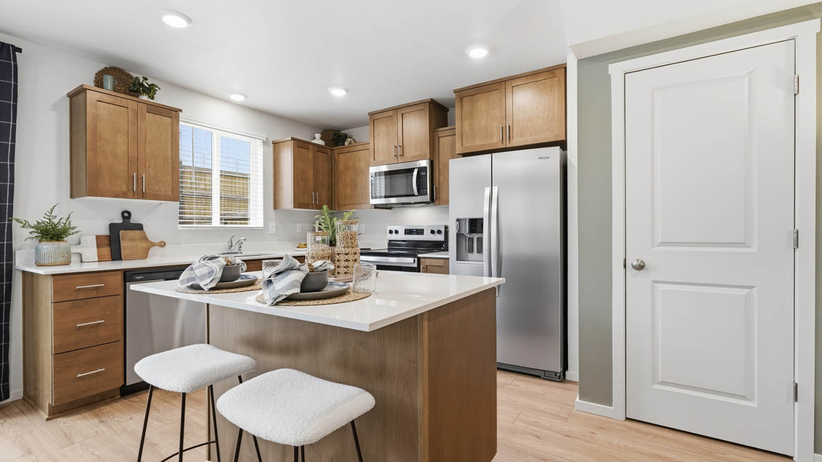 Kitchen with shaker cabinets, quartz counters, stainless steel appliances, pantry, and an island with a breakfast bar