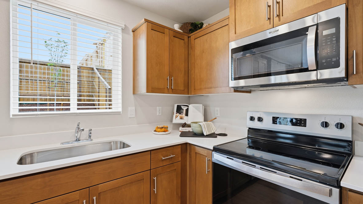 Kitchen with shaker cabinets, quartz counters, stainless steel appliances, pantry, and an island with a breakfast bar