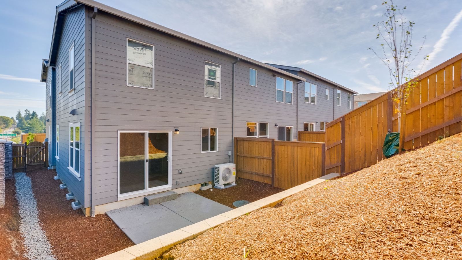 fully fenced backyard with bark chips and a patio