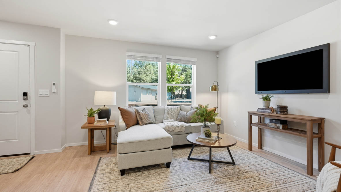 Thunder Ridge Great room with a tv, couch and pillows, chair, wood coffee table, laminate flooring, a lamp, and windows