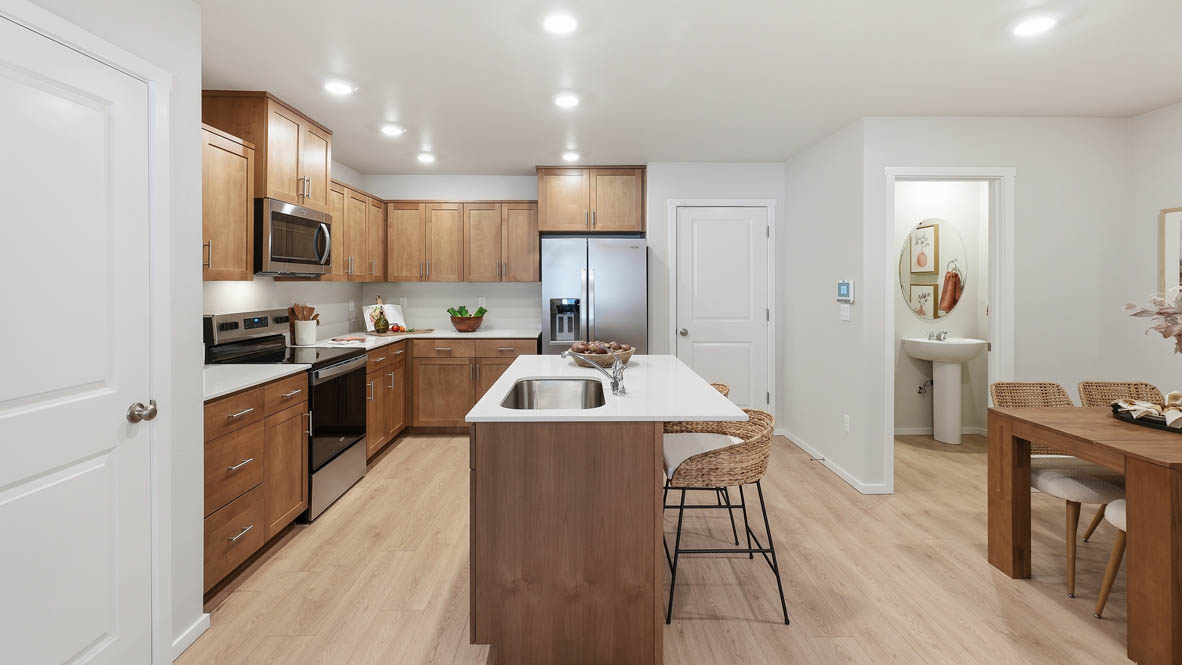 Thunder Ridge kitchen with stained shaker style cabinets and brushed nickel pulls with solid surface countertops and stainless steel appliances