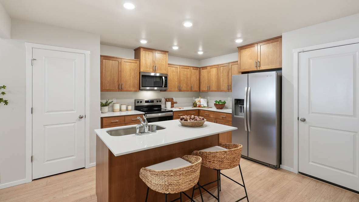 Thunder Ridge kitchen with stained shaker style cabinets and brushed nickel pulls with solid surface countertops and stainless steel appliances