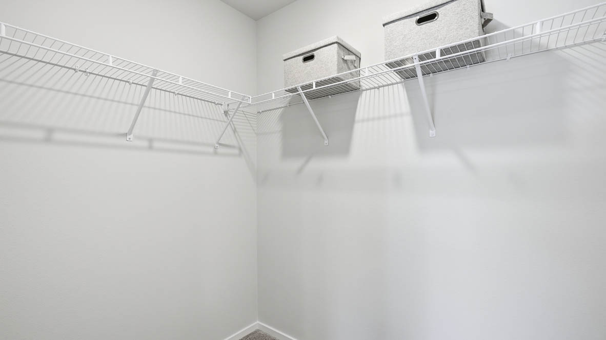 Thunder Ridge walk in closet with white wire shelving and clothes hanging on the racks and baskets on the shelves