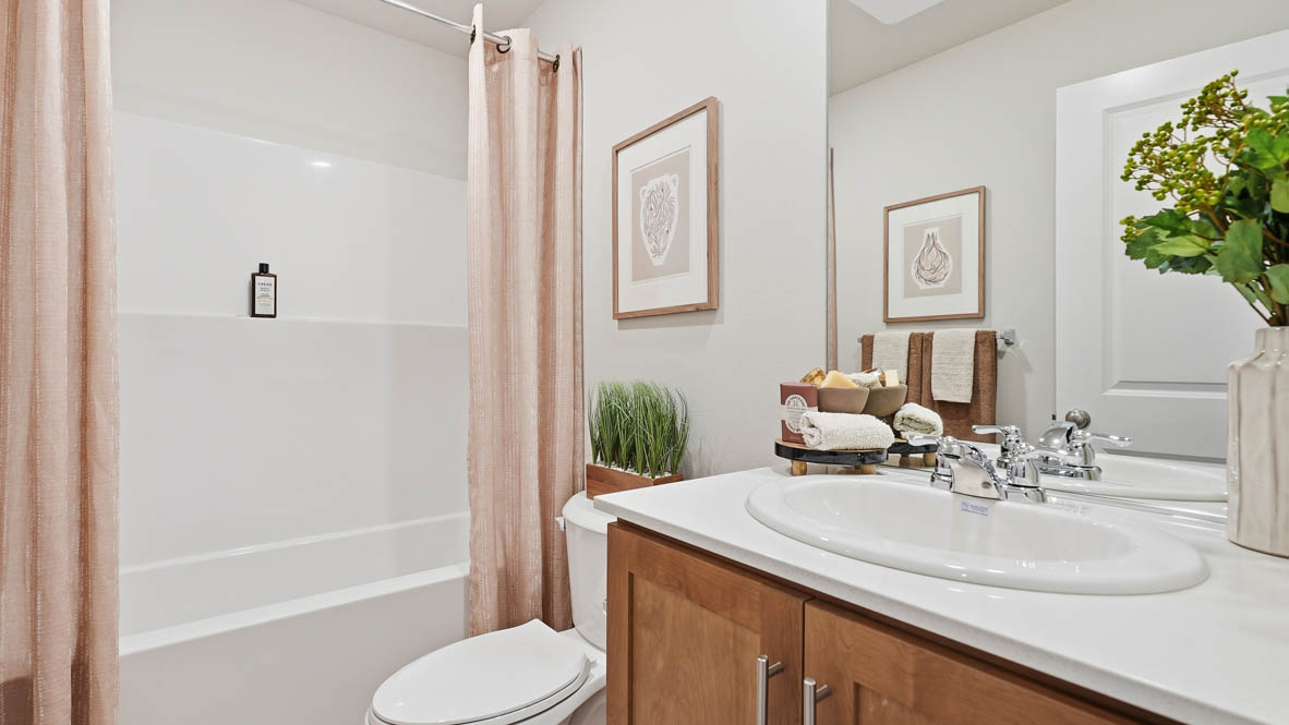 Thunder Ridge secondary bathroom with tub shower and shaker style cabinets under a single sink vanity with solid surface countertops