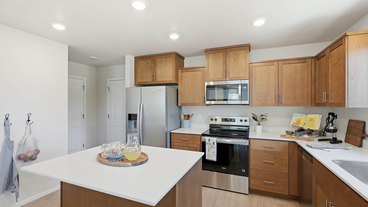 Thunder Ridge kitchen with stained shaker style cabinets and brushed nickel pulls with solid surface countertops and stainless steel appliances