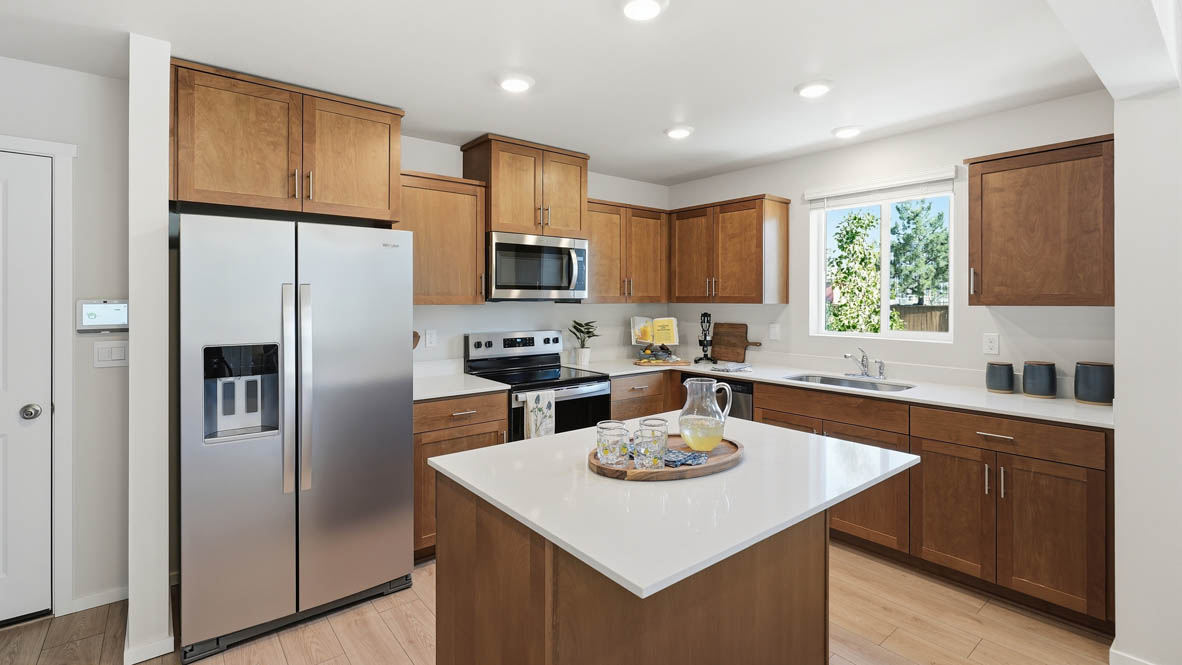 Thunder Ridge kitchen with stained shaker style cabinets and brushed nickel pulls with solid surface countertops and stainless steel appliances