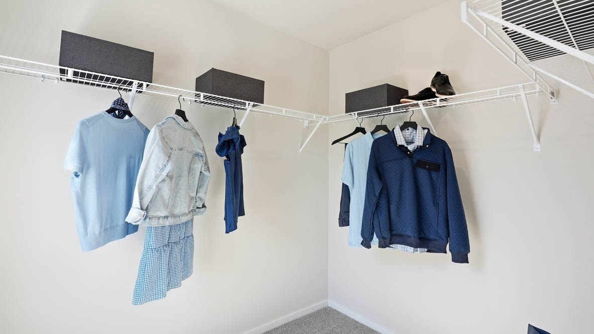 Thunder Ridge walk in closet with white wire shelving and clothes hanging on the racks and baskets on the shelves