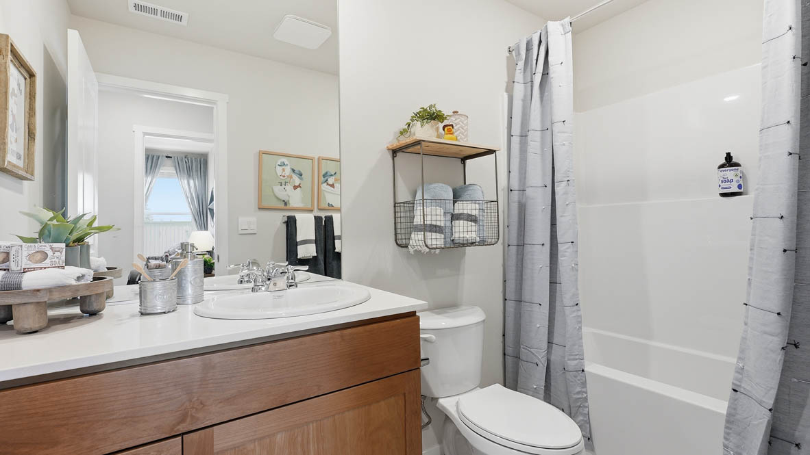 Thunder Ridge secondary bathroom with tub shower and shaker style cabinets under a single sink vanity with solid surface countertops