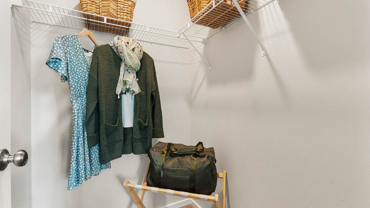 Thunder Ridge walk in closet with white wire shelving and clothes hanging on the racks and baskets on the shelves