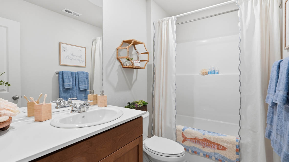Thunder Ridge bathroom with tub shower, toilet, vanity, mirror, and stained cabinets