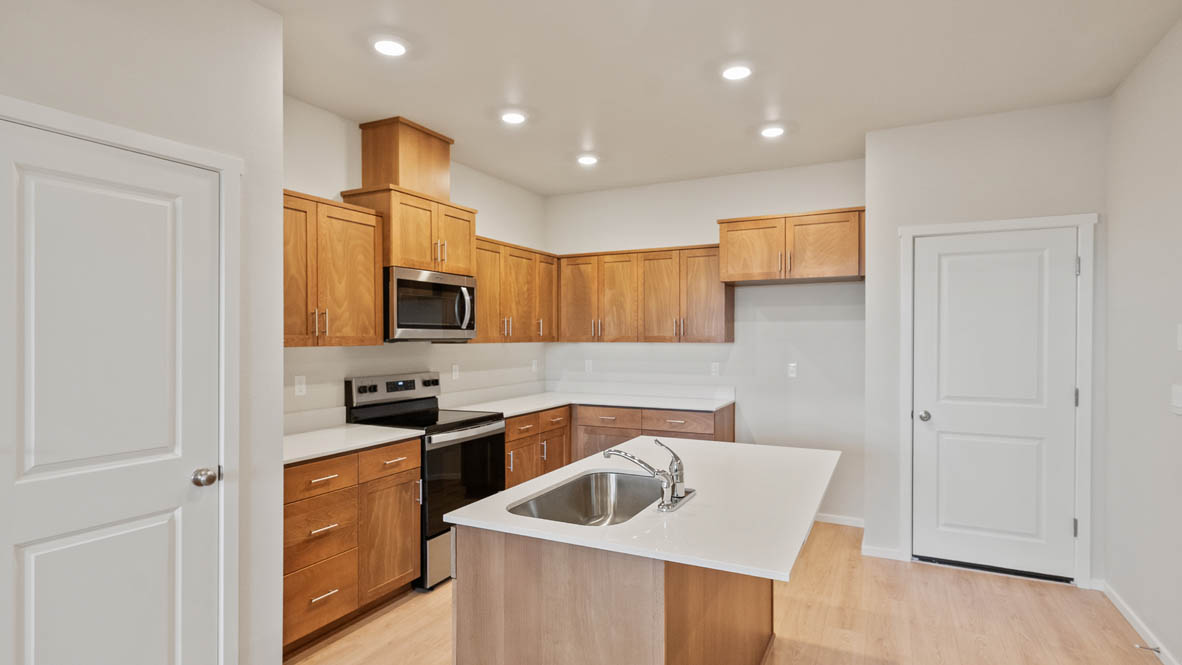 Ponderosa kitchen with stained shaker style cabinets and brushed nickel pulls with solid surface countertops and stainless steel appliances