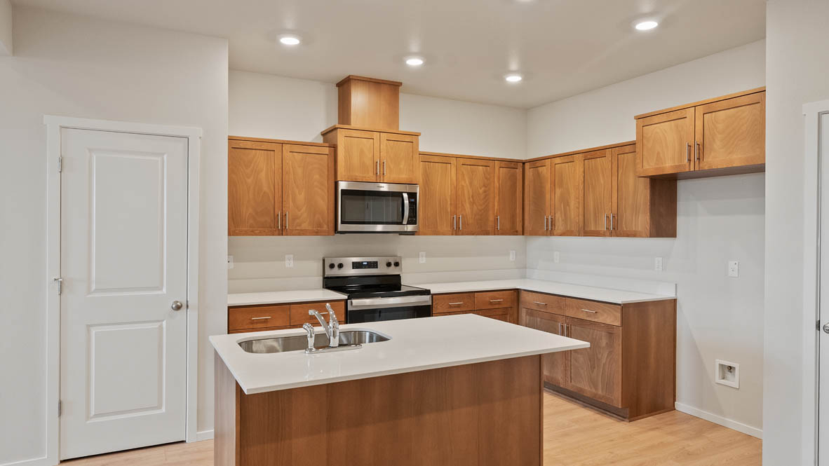 Ponderosa kitchen with stained shaker style cabinets and brushed nickel pulls with solid surface countertops and stainless steel appliances