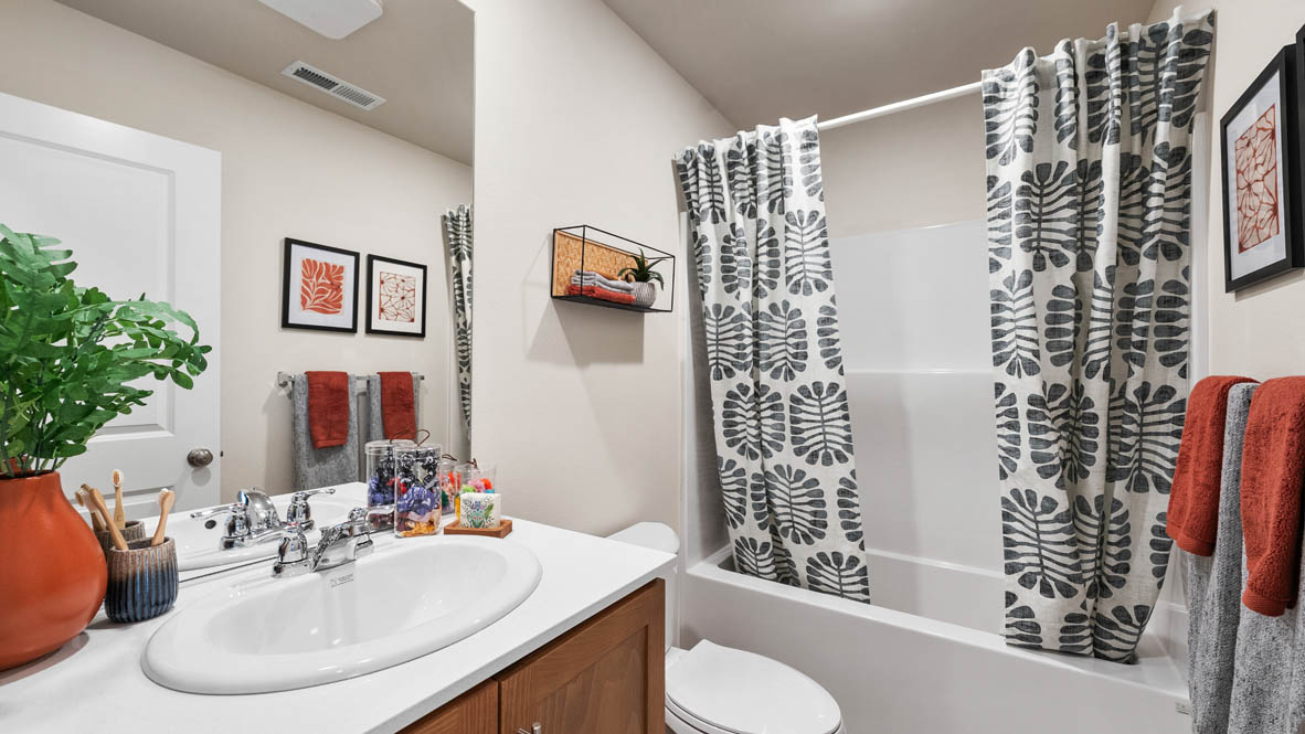 Ponderosa secondary bathroom with tub shower and shaker style cabinets under a single sink vanity with solid surface countertops
