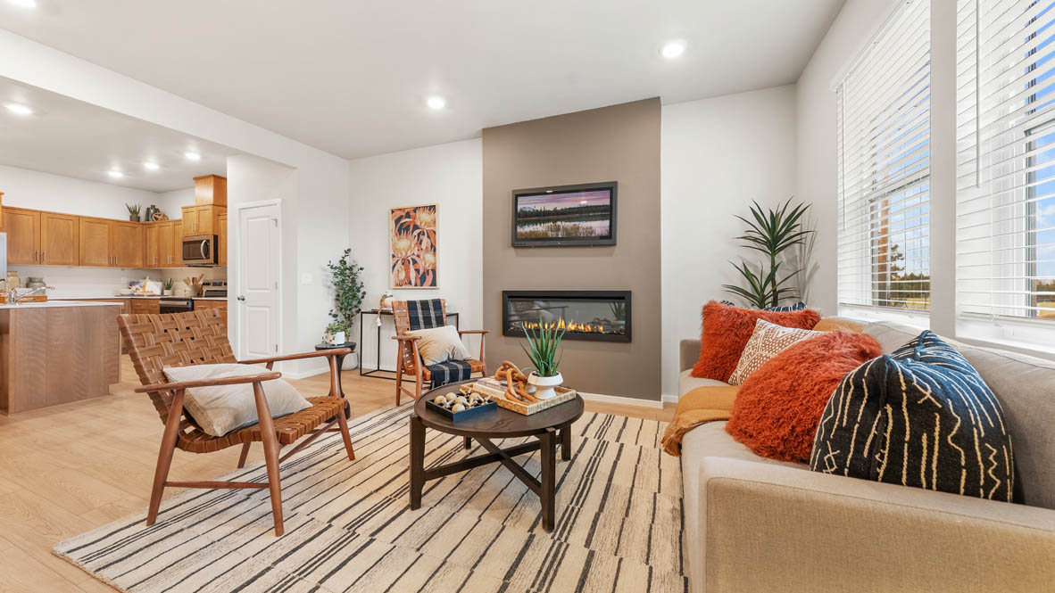 Ponderosa Great room with a white couch and pillows, electric fireplace, chair, white rug, wood coffee table, laminate flooring, a lamp, and windows