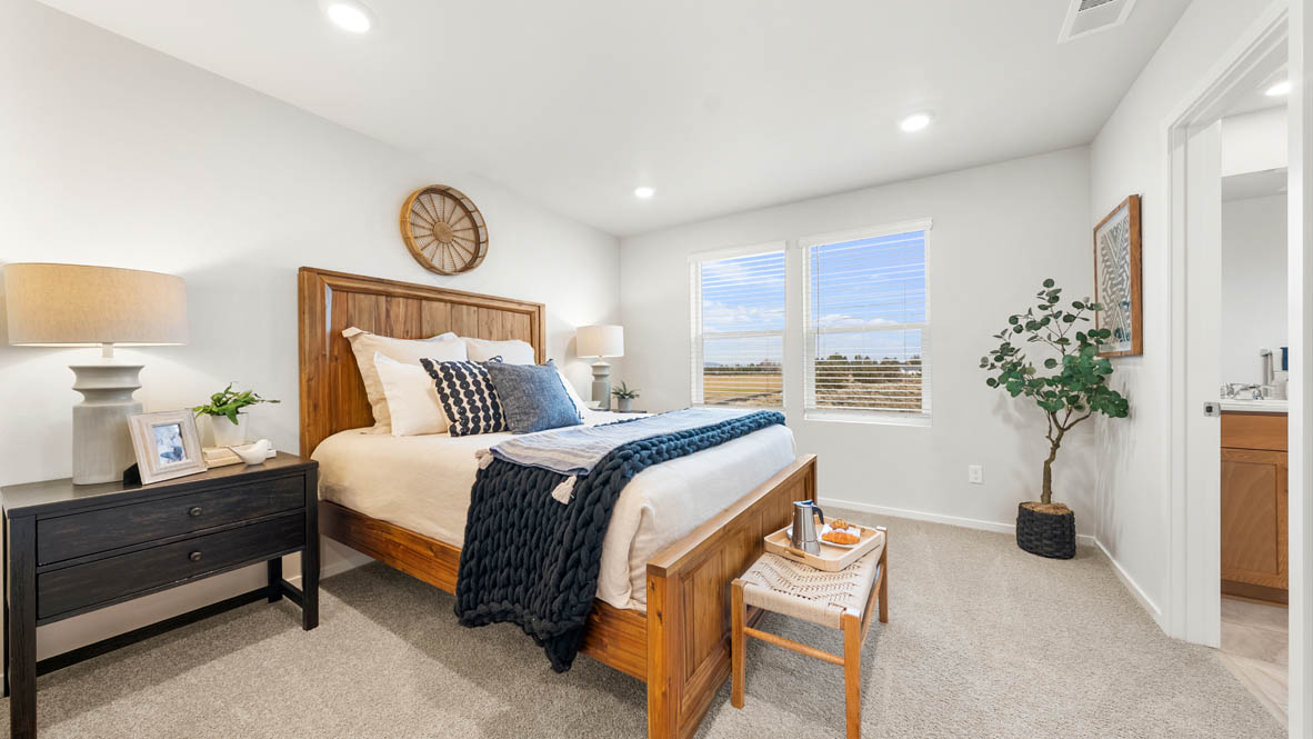 Ponderosa primary bedroom with carpet and with white accent wall and wooden side tables