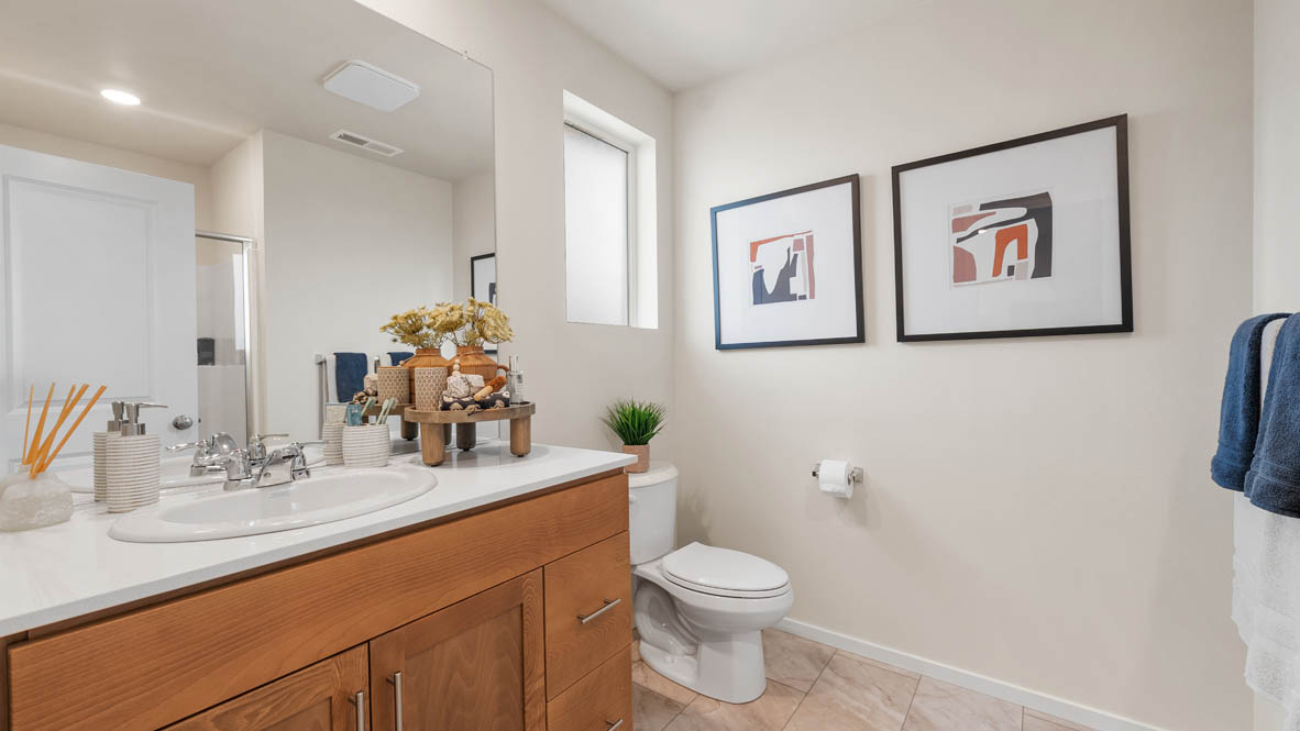 Ponderosa primary bathroom with stained shaker style cabinets with brushed nickel pulls under solid surface countertops