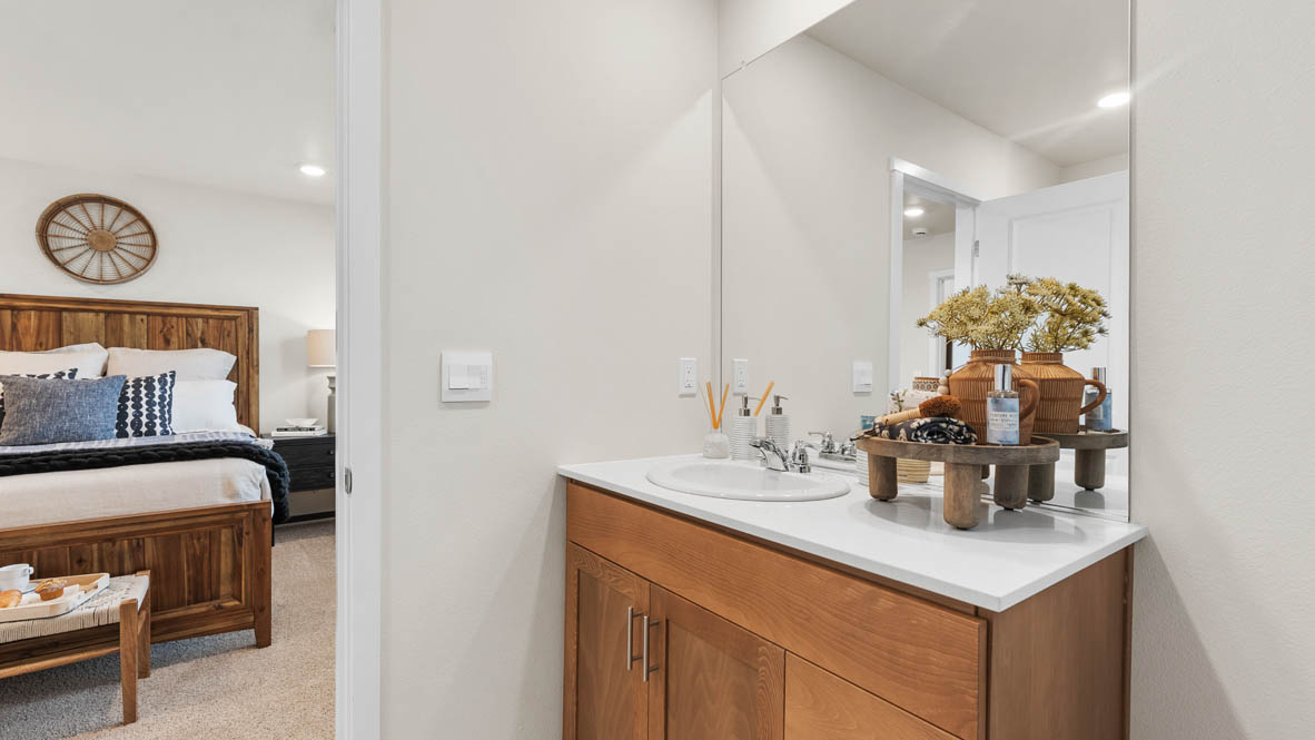 Ponderosa primary bathroom with stained shaker style cabinets with brushed nickel pulls under solid surface countertops