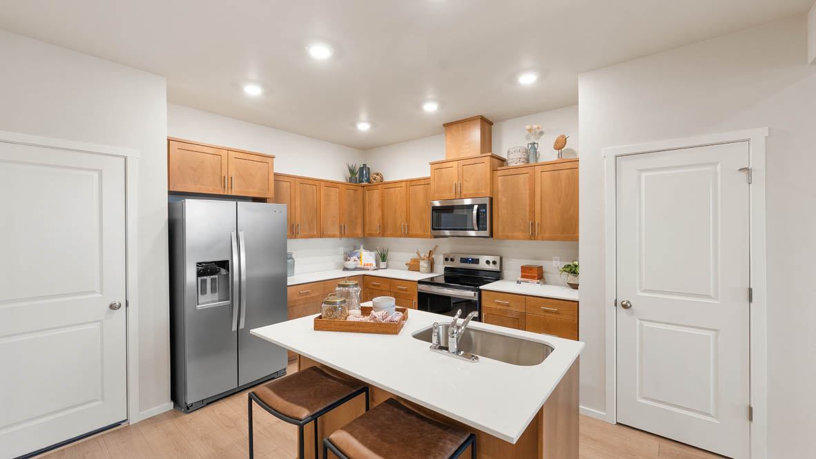 Ponderosa kitchen with stained shaker style cabinets and brushed nickel pulls with solid surface countertops and stainless steel appliances
