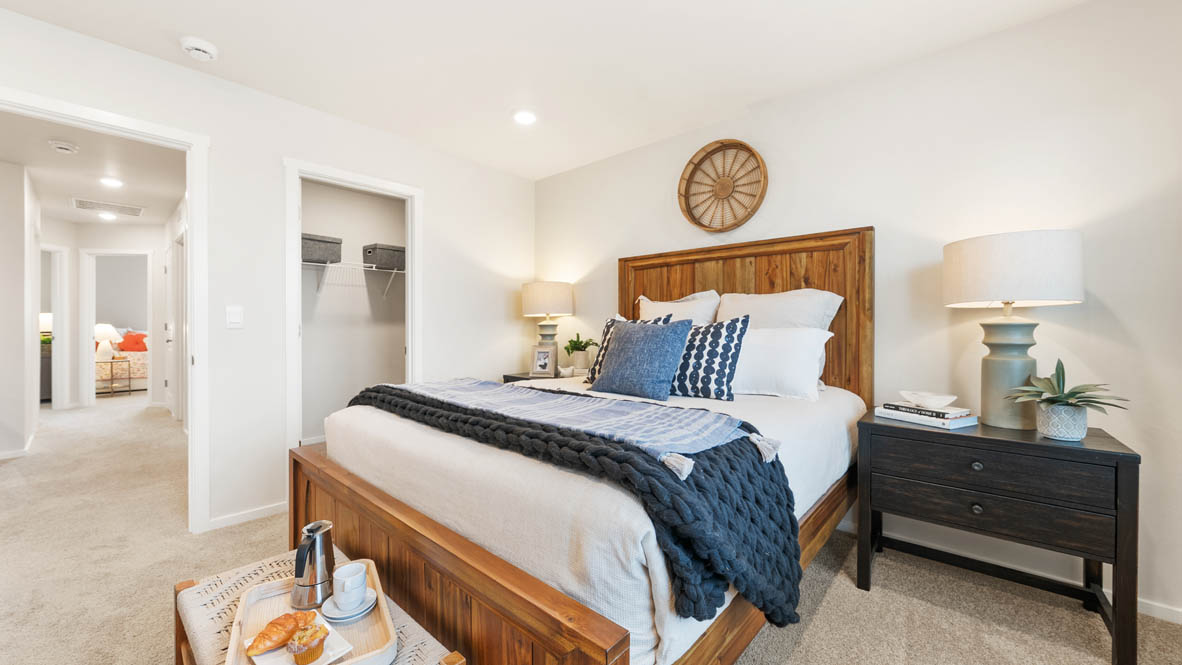 Ponderosa primary bedroom with carpet and with white accent wall and wooden side tables