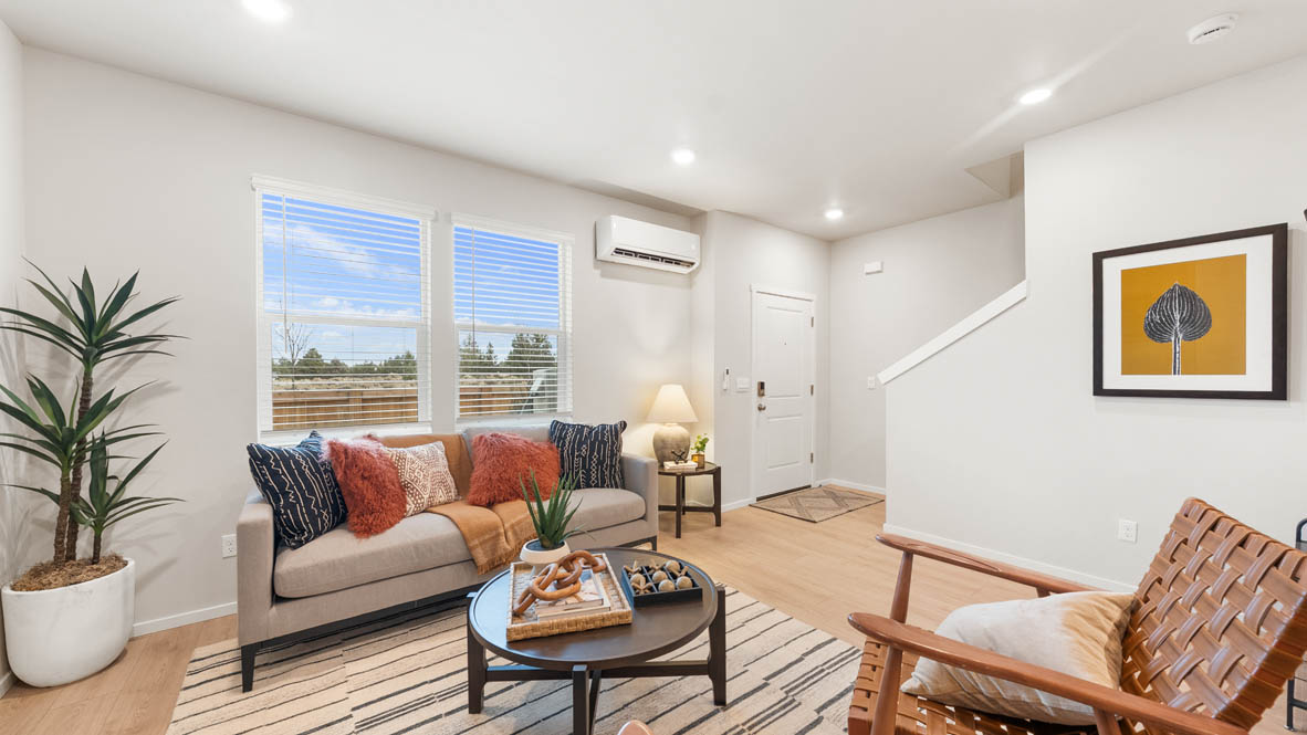 Ponderosa Great room with a white couch and pillows, electric fireplace, chair, white rug, wood coffee table, laminate flooring, a lamp, and windows