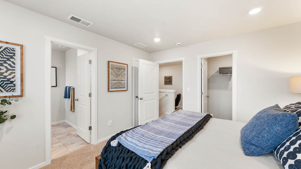 Ponderosa primary bedroom with carpet and with white accent wall and wooden side tables