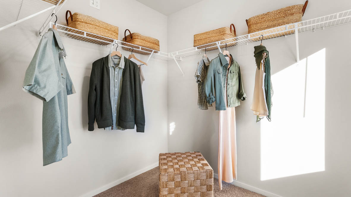Ponderosa walk in closet with white wire shelving and clothes hanging on the racks and baskets on the shelves