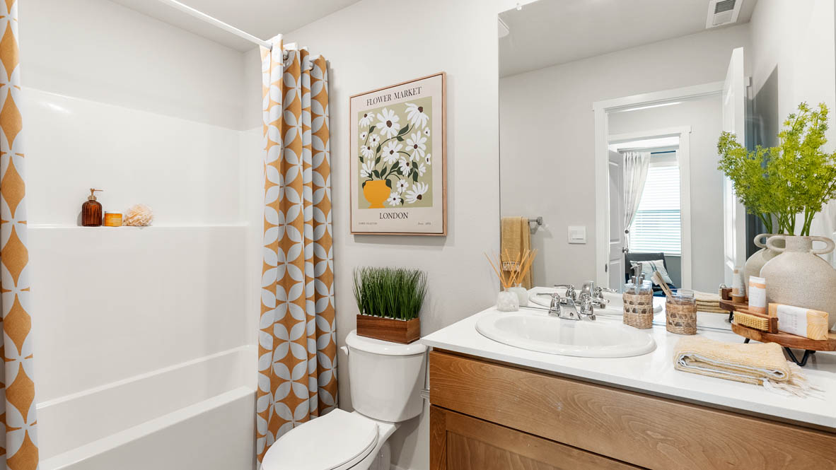 Ponderosa secondary bathroom with tub shower and shaker style cabinets under a single sink vanity with solid surface countertops