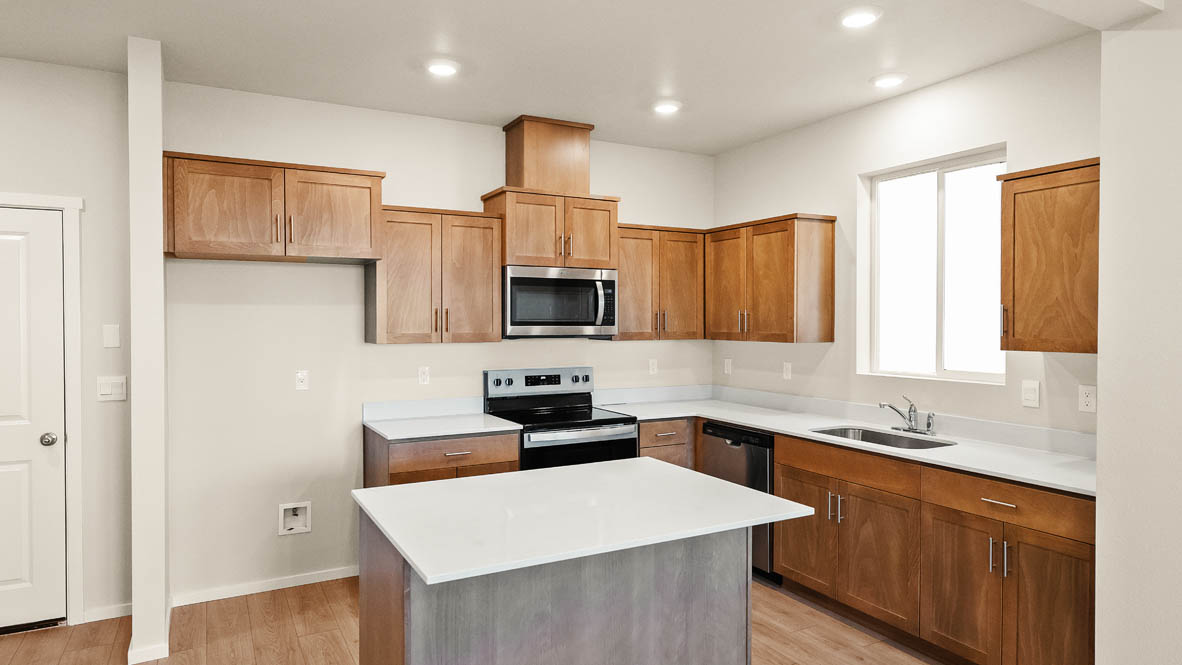 Ponderosa kitchen with stained shaker style cabinets and brushed nickel pulls with solid surface countertops and stainless steel appliances