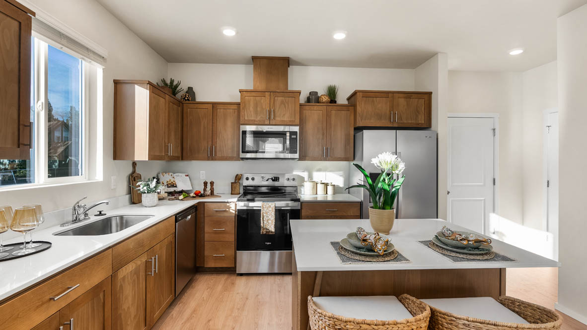 Ponderosa kitchen with stained shaker style cabinets and brushed nickel pulls with solid surface countertops and stainless steel appliances