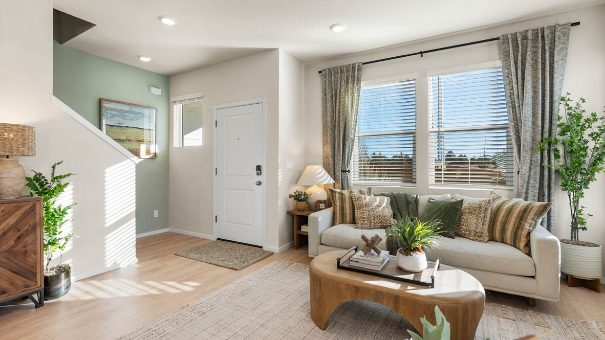 Ponderosa Great room with a white couch and pillows, chair, wood coffee table, laminate flooring, a lamp, and windows