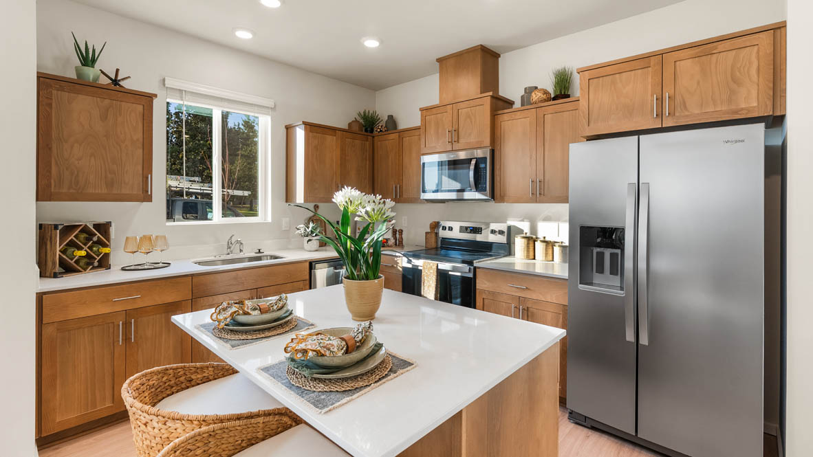 Ponderosa kitchen with stained shaker style cabinets and brushed nickel pulls with solid surface countertops and stainless steel appliances