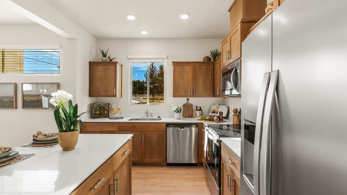 Ponderosa kitchen with stained shaker style cabinets and brushed nickel pulls with solid surface countertops and stainless steel appliances
