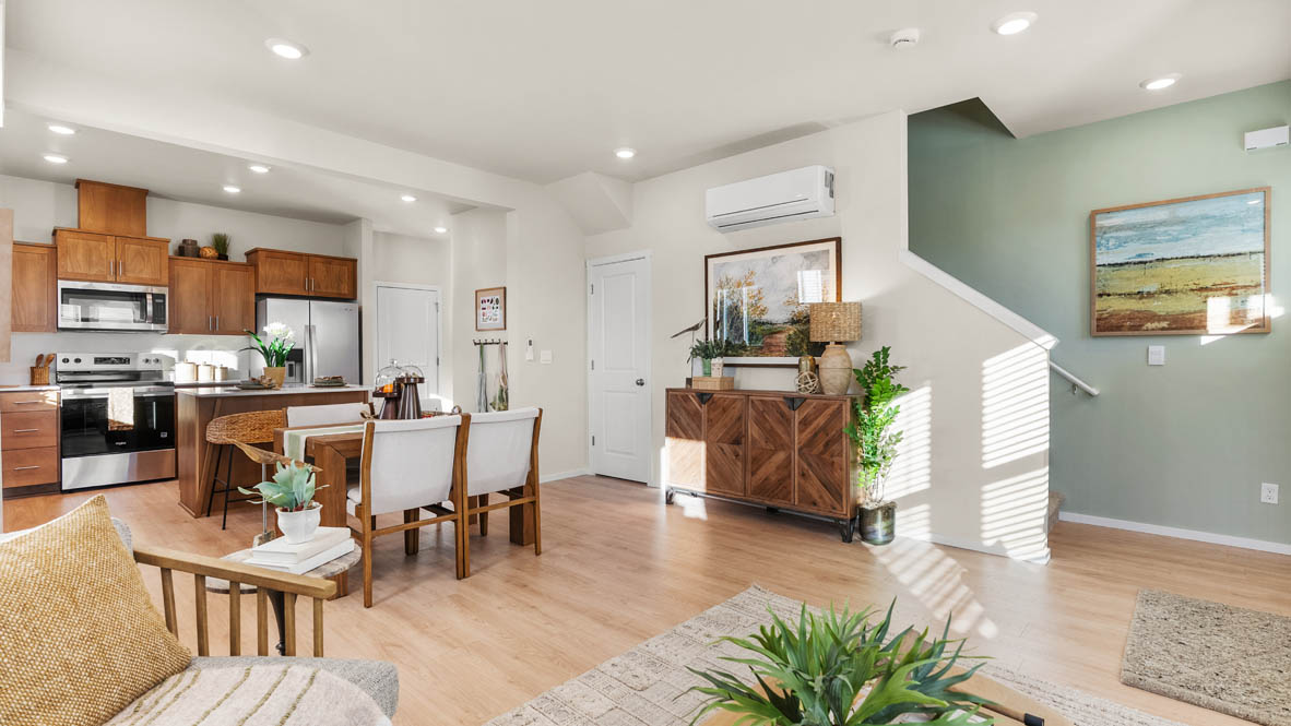 Ponderosa Great room with a white couch and pillows, chair, wood coffee table, laminate flooring, a lamp, and the kitchen in the background