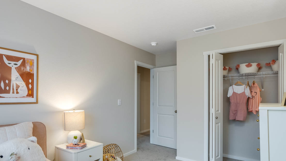 Ponderosa Bedroom with pink bedding, white walls, a white dresser with pink accents and a bedside lamp